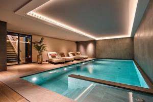 a swimming pool in a room with a couch and chairs at Eilandhotel Texel - Nieuw geopend hotel in De Cocksdorp