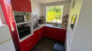 una piccola cucina con armadi rossi e una finestra di Bungalow LEWOZETAJ a Sainte-Anne