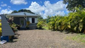 una piccola casa bianca con un vialetto di ghiaia di Bungalow LEWOZETAJ a Sainte-Anne
