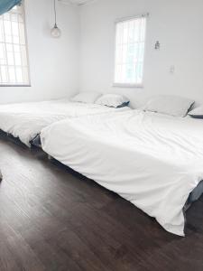 two beds in a room with white sheets and wood floors at Nằm Mơ 1 Homestay - chi Nhánh Ngô Thì Sỹ in Da Lat