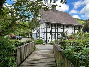 a white and black house with a wooden bridge at Fachwerkliebe Baudenkmal Ornes in Olsberg