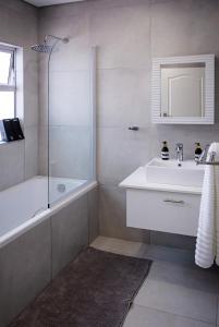 a bathroom with a tub and a sink and a shower at Dulce Vita Self-Catering Duet in Bloemfontein +28 photos