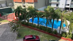 a red car parked next to a swimming pool at Apartamento Complejo La Manzana in Corrientes