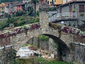 a stone bridge over a river with flowers at Little Home in Pignone
