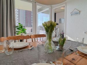 a dining room table with a vase of flowers on it at FeWo Sielblick mit Balkon - Horumersiel in Horumersiel