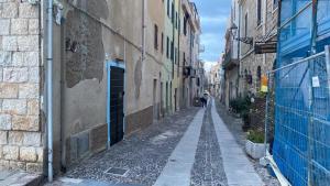 an empty alley with a person walking down the street at La Scogliera in Alghero