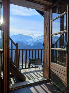 a chair sitting on a balcony with a view of mountains at Demeure Sauvage - Étage 2 in Villard-Reculas