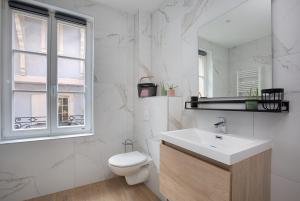 a white bathroom with a toilet and a sink at Au coeur d'Obernai in Obernai