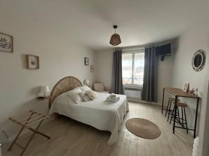 Un dormitorio con una cama y una mesa y una ventana. en Hôtel La Coursive, en Saint-Pierre-dʼOléron