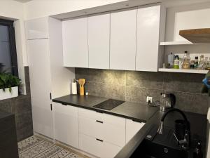 a kitchen with white cabinets and a black counter top at Przytulna kawalerka blisko centrum in Krosno