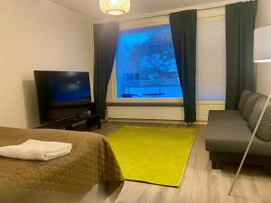 a bedroom with a bed and a couch and a television at HUTTUNEN 2 - Ihqu kaksio mahtavalla sijainnilla! in Iisalmi