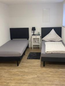 two beds in a room with a desk and a bed at BayrischGut Ferienwohnung in Orschweier