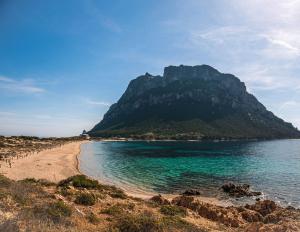 - une vue sur une plage avec une montagne en arrière-plan dans l'établissement Casa Lantana, à Porto Taverna
