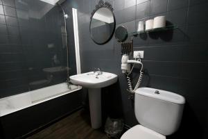 a bathroom with a toilet and a sink and a mirror at Hotel Las Vegas in Colunga