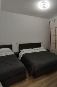 Un dormitorio con dos camas y una pared blanca. en SanSiroHomeRhofieraMilano, en Pero