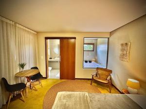 a room with a bed and a table and chairs at Vila Puru - 6 apartamentos - 2 com jacuzzi e 4 sem - Café da manhã à parte in Alto Paraíso de Goiás