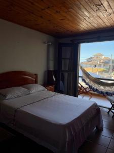 a bedroom with a bed and a window with a hammock at Duplex La Moana em Itaúna - Saquarema RJ in Saquarema
