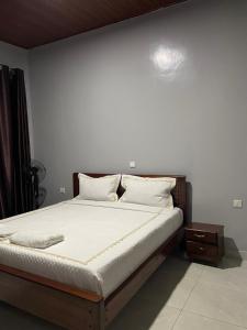 a bed with white sheets and pillows in a bedroom at Ritha Motel Apartment in Kigali