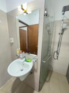 une salle de bain avec un lavabo et une douche avec un miroir dans l'établissement Canterbury Golf Resort Apartment, à Piliyandala