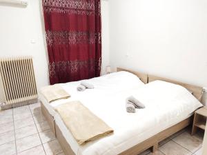 2 camas en una habitación con cortina roja en Cathrine's Apartment, en Tríkala 3 fotos más