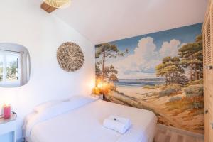 Un dormitorio con una cama blanca con un cuadro en la pared. en Cabana & On dirait le Sud, en Flacé-lès-Mâcon