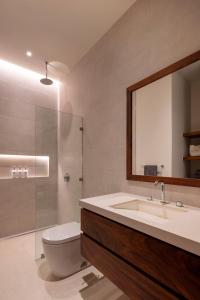 een badkamer met een wastafel, een toilet en een spiegel bij Haven Nosara in Nosara