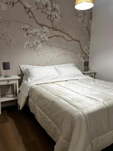 1 dormitorio con cama blanca y pared de flores en Appartamento Gna Turidda, en Ragusa