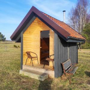a small shed with two chairs in a field at Forest edge in Saugos +9 photos