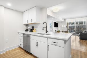 a white kitchen with a sink and a living room at Comfortable Apartment with Top Amenities in Arlington