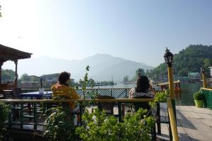 two people sitting at a table near a body of water at Hotel sea face in Srinagar