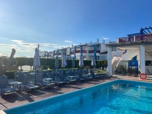a pool with chairs and umbrellas next to a building at MileniKo Beach Villa in Sozopoli