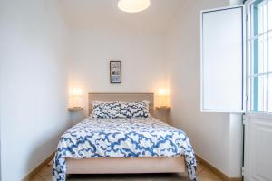 a bedroom with a bed with a blue and white comforter at HAUS NUNES by Stay in Alentejo in Vila Nova de Milfontes
