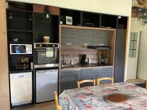 a kitchen with stainless steel appliances and a table at La Tour du Sorbey - Gîte Nature Familial - Piscine - 3 à 6 Pax in Monségur
