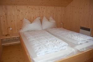 a bed in a wooden room with white pillows at Chalet Sonnenschein in Hohentauern +30 photos