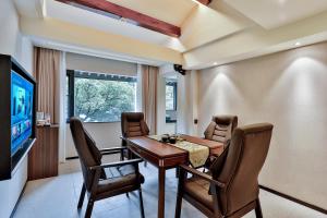 a dining room with a table and chairs and a television at Yurong West Lake Cottage Resort Hotel Hangzhou in Hangzhou