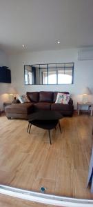 a living room with a brown couch in a room at Pieds dans l'eau - La Villa Crique aux tortues in Zonza