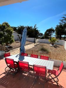 einen weißen Tisch mit roten Stühlen und einem blauen Schirm in der Unterkunft maison 50 m de la plage in La Guérinière