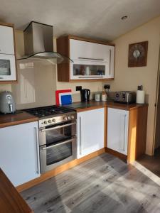 a kitchen with white cabinets and a stove top oven at B&R 18 Gleneagles in Turnberry
