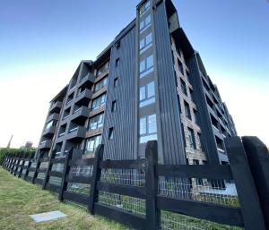 巴拉斯港Dpto costero vista al lago, piscina y jacuzzi的围栏后面的黑色公寓大楼