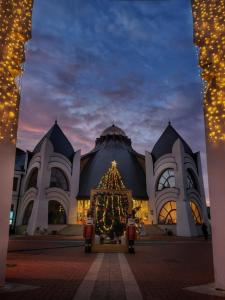 a christmas tree in front of a building with lights at Pipacs Apartman in Makó
