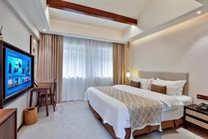 a hotel room with a bed and a flat screen tv at Yurong West Lake Cottage Resort Hotel Hangzhou in Hangzhou