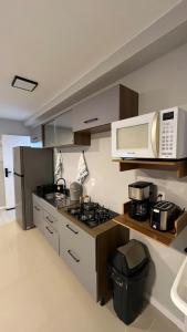 a kitchen with a stove and a microwave at Apartamento semi-Novo Litoral Itajaí Sc in Itajaí