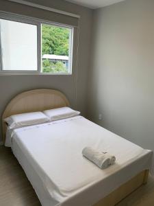 a white bed in a bedroom with a window at Apartamento semi-Novo Litoral Itajaí Sc in Itajaí
