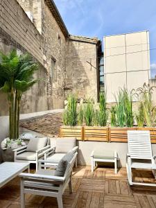 a patio with white chairs and tables and plants at Superbe appartement grande terrasse centre ville St Rémy in Saint-Rémy-de-Provence