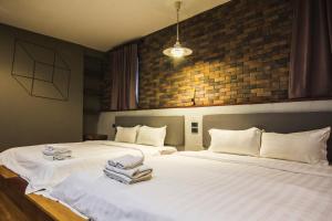 two beds in a room with white sheets and towels at Space59 Hotel in Ratchaburi