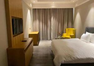 a hotel room with a large bed and a yellow chair at Hoatel Abha in Alīgarh
