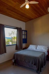 a bedroom with a bed with a ceiling fan and a window at Casa Portal do Pati in Lençóis