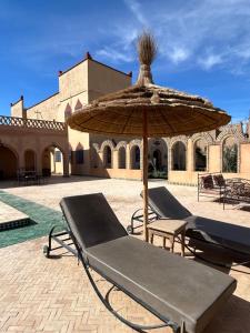 a patio with a bench and an umbrella at Dar Marhaba Merzouga in Merzouga