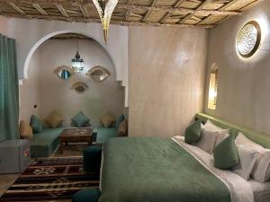 a bedroom with a green bed and a couch at Dar Marhaba Merzouga in Merzouga +40 photos