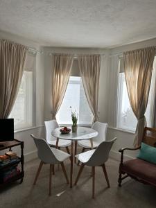 ein Wohnzimmer mit Tisch und Stühlen und Fenstern in der Unterkunft Home By The Sea in Eastbourne